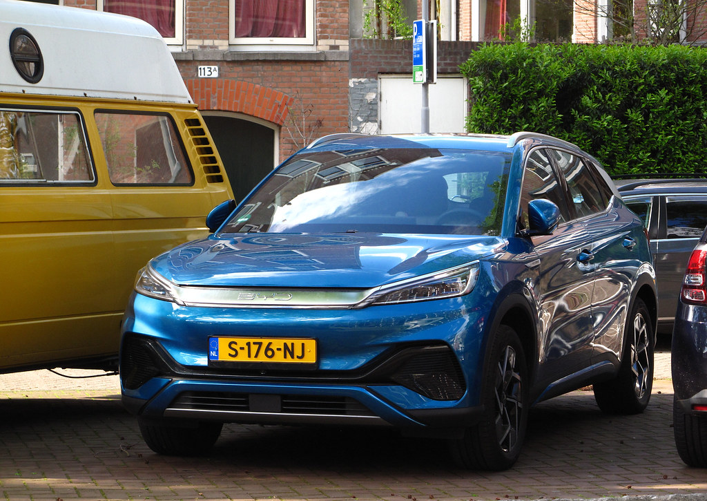 Blue BYD Atto 3 electric SUV parked on a residential street, showing front three-quarter view with distinctive BYD grille and headlights.