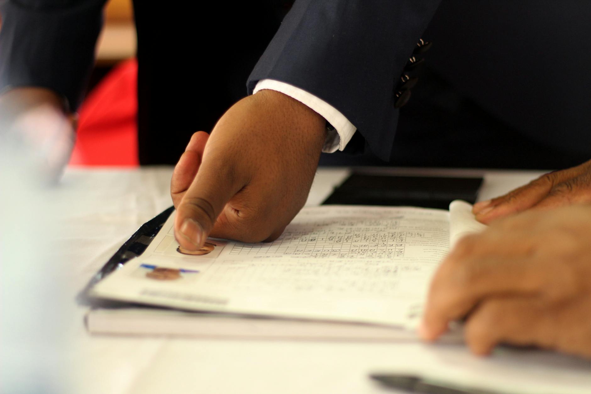 Two people in business attire reviewing documents across a table during a formal meeting