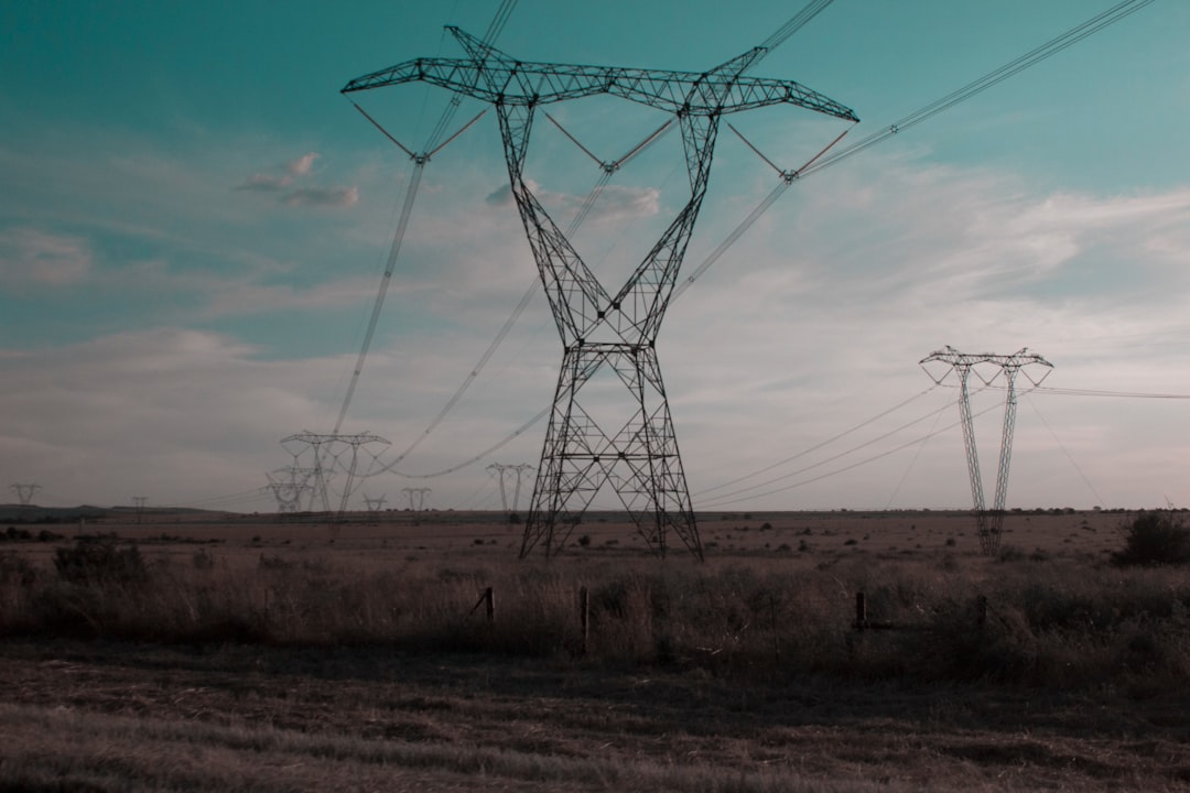 High-voltage transmission towers and power lines stretching across open terrain at dusk