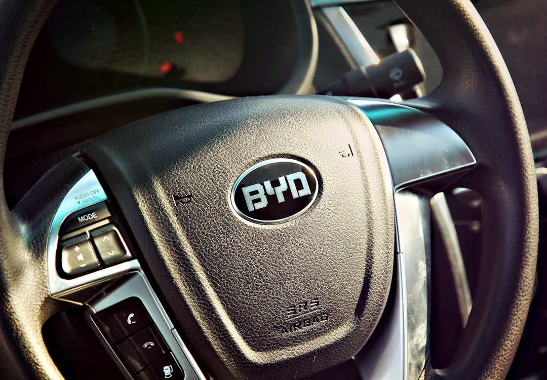 BYD steering wheel with brand logo and multifunction controls, showing MODE button and instrument cluster in background
