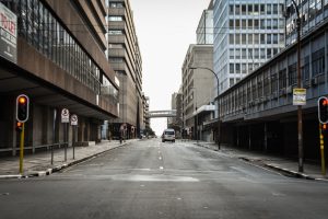Empty urban street with modern office buildings, traffic lights, and pedestrian bridge connecting buildings overhead