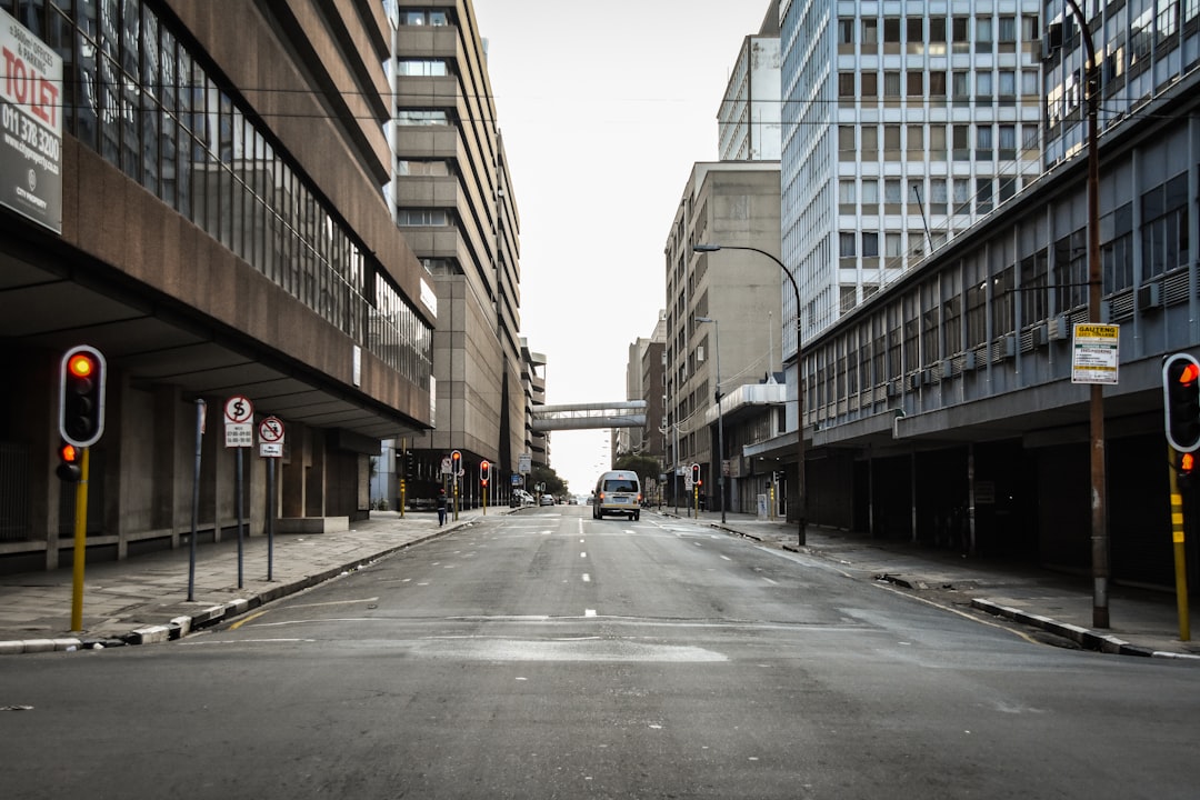 Empty urban street with modern office buildings, traffic lights, and pedestrian bridge connecting buildings overhead