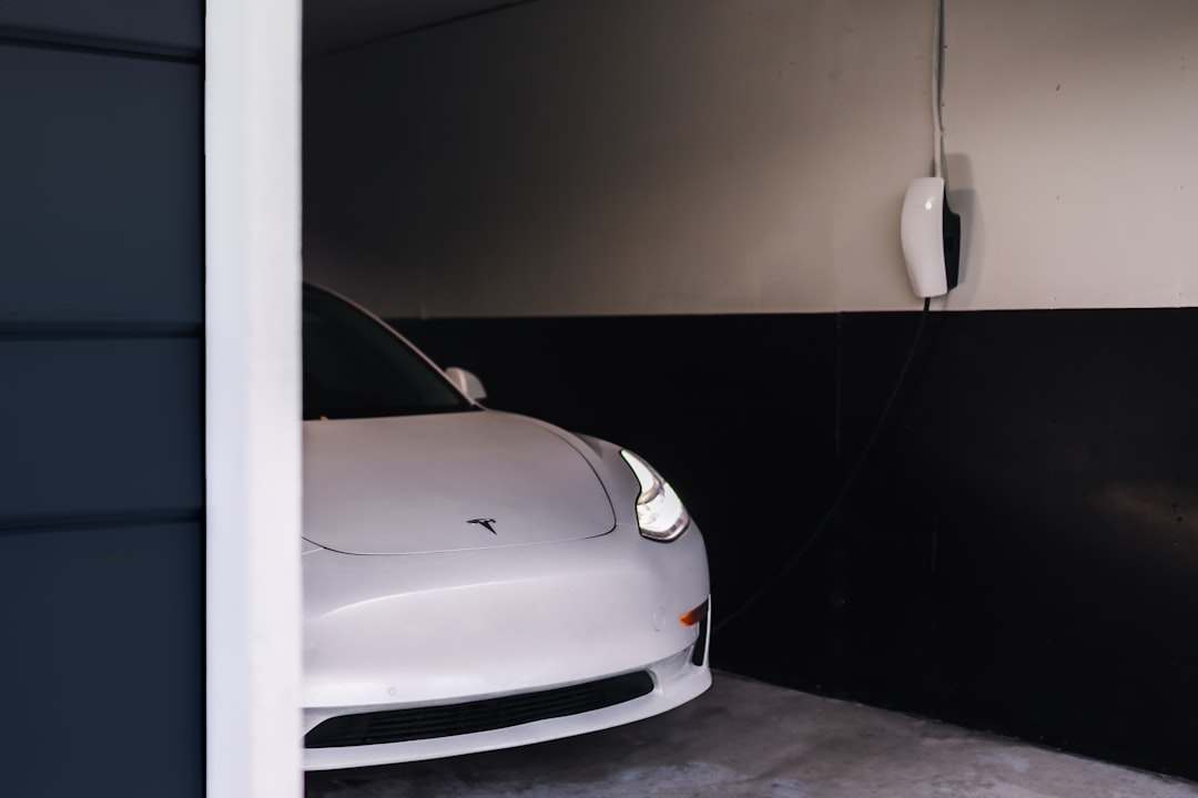 White wallbox EV charger mounted on garage wall with charging cable connected to a white electric vehicle