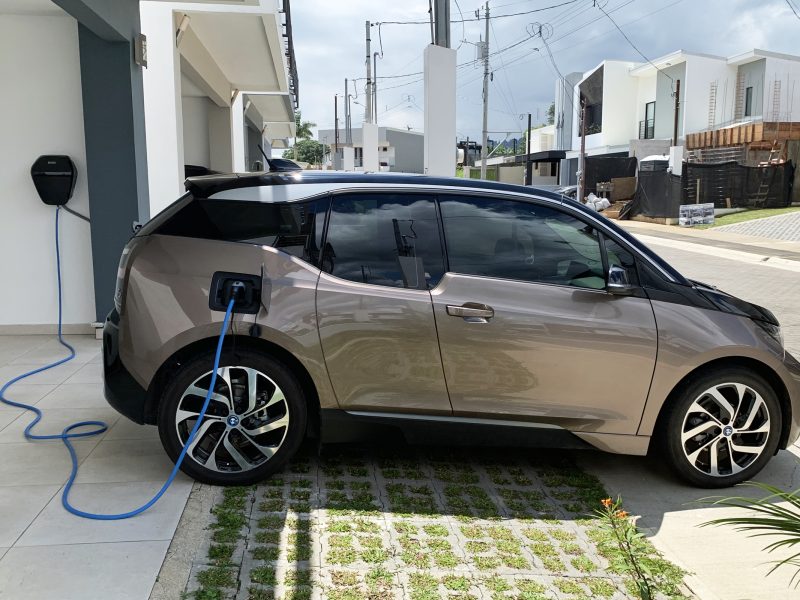 BMW i3 plugged into a Level-2 home wallbox in a residential driveway