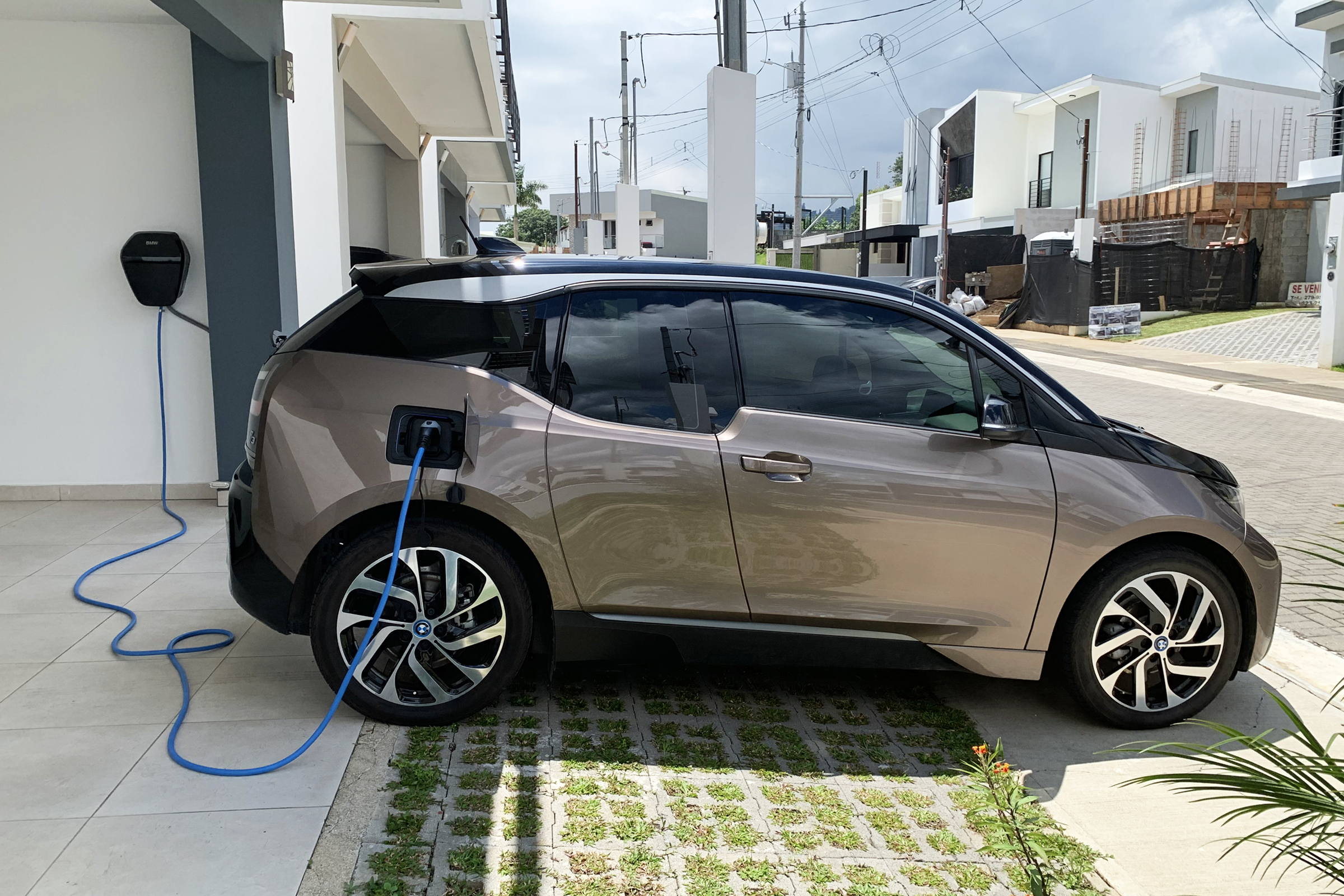 BMW i3 plugged into a Level-2 home wallbox in a residential driveway