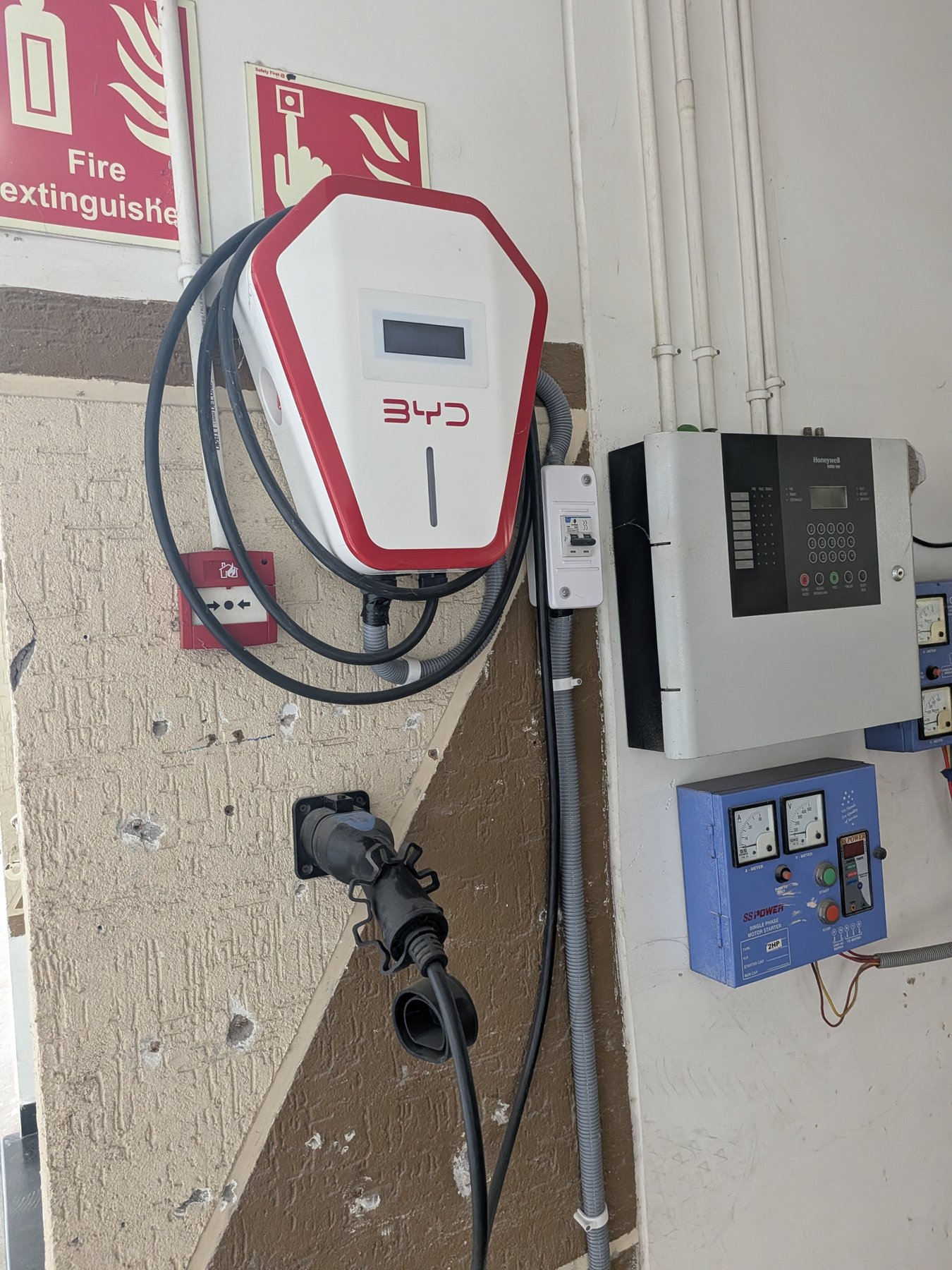 A BYD-branded home wallbox wall-mounted beside an electrical distribution board