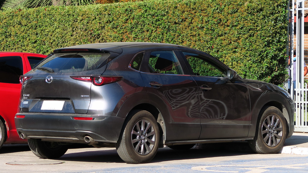 Side-by-side comparison of Geely E5 electric SUV and Mazda CX-30 petrol crossover with cost breakdown charts for South Africa
