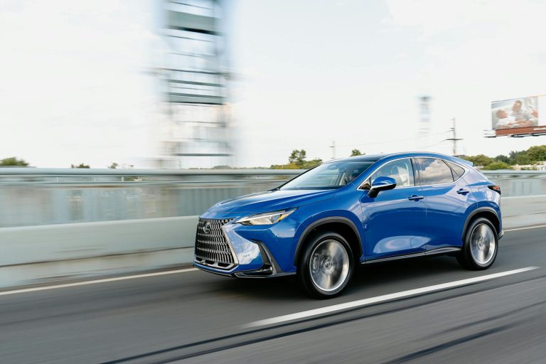 Blue Lexus RZ electric SUV in motion showing front three-quarter view with distinctive spindle grille design