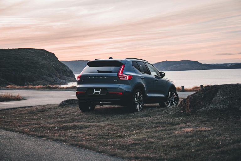 A Volvo XC40 SUV parked near a scenic bay during a serene sunset, highlighting its elegant design and outdoor backdrop.