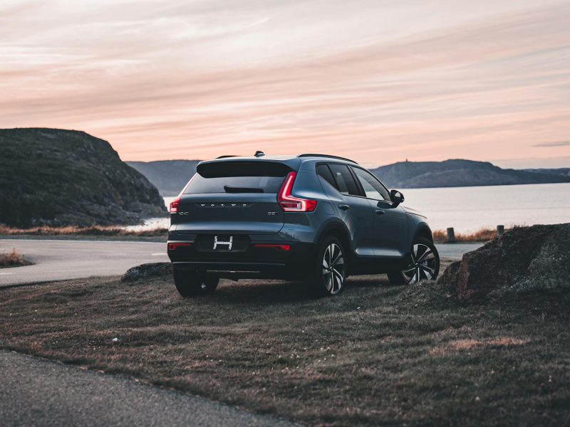 A Volvo XC40 SUV parked near a scenic bay during a serene sunset, highlighting its elegant design and outdoor backdrop.