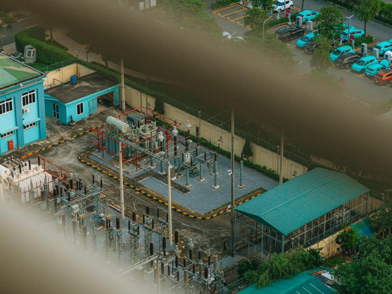 An overhead view of a city electrical substation with surrounding infrastructure.