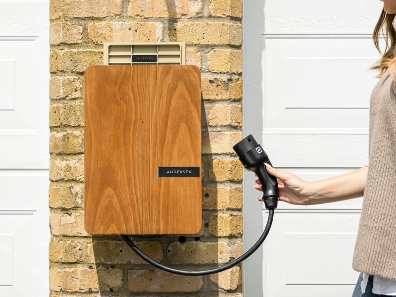 Wooden EV home charger installed on a brick wall for sustainable transportation.