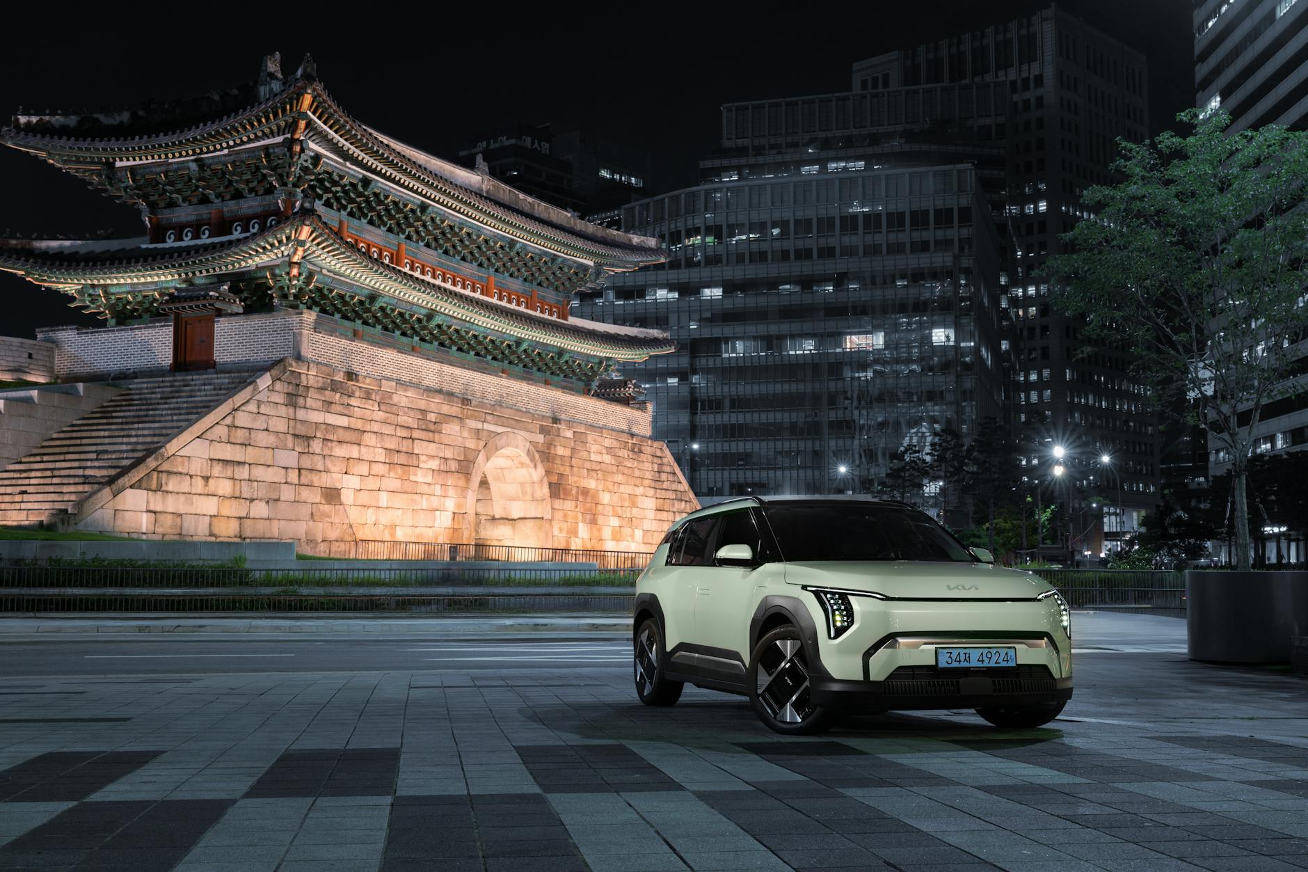 Electric SUV parked near the illuminated historic Namdaemun Gate in Seoul at night.