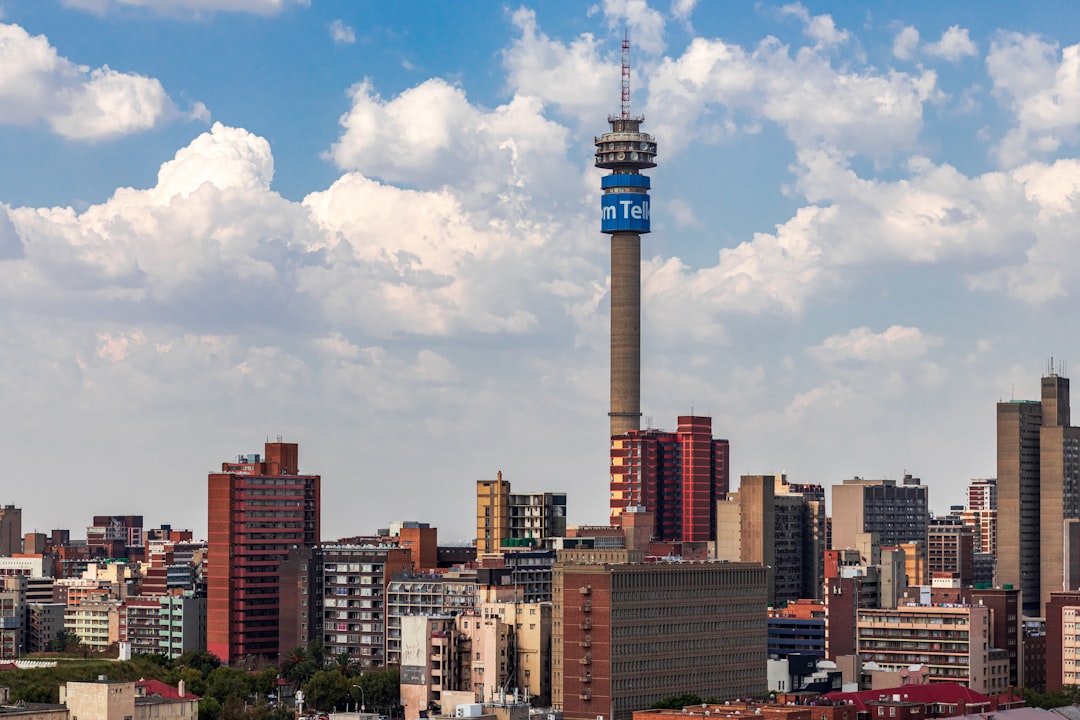 Johannesburg skyline featuring the Hillbrow Tower with blue Telkom branding rising above residential and commercial buildings