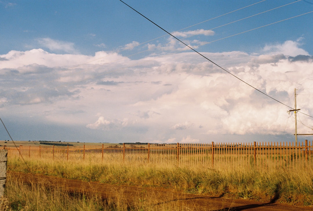 Electrical power lines and utility pole stretching across a rural landscape under a dramatic cloudy sky.