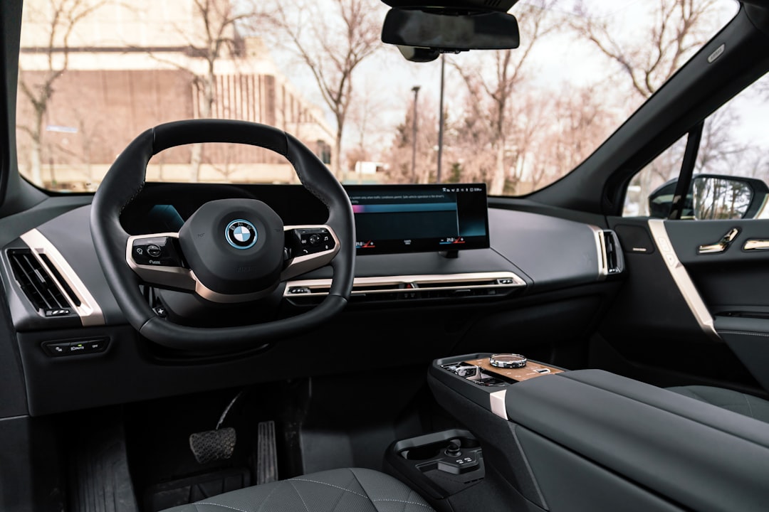 BMW electric vehicle interior showing curved iDrive display, digital instrument cluster, and premium dashboard with panoramic glass roof