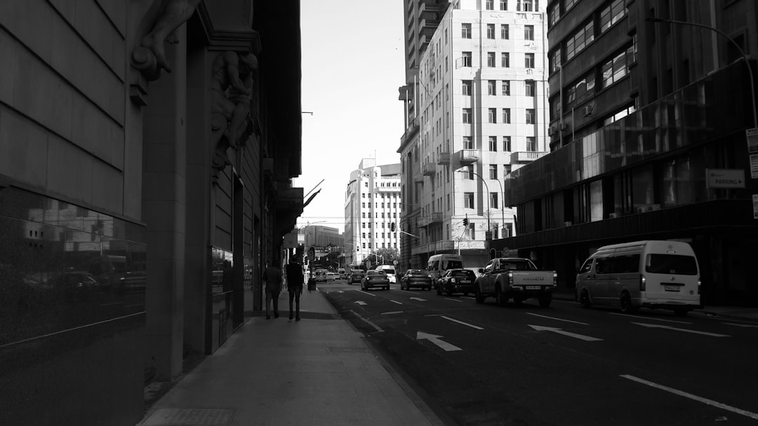Urban street scene showing multiple lanes of traffic between modern high-rise buildings during daytime