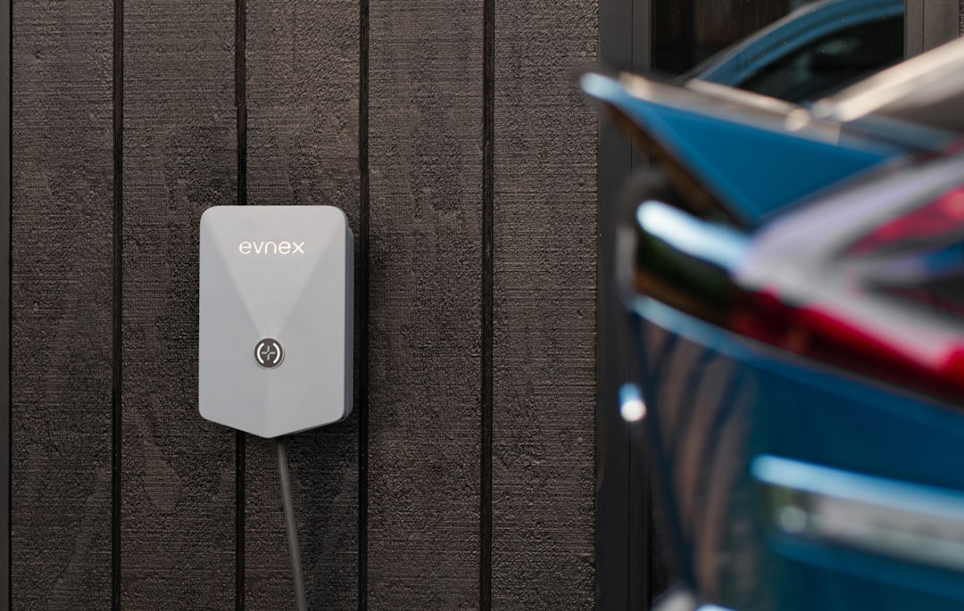 Evnex branded white EV wallbox charger mounted on dark wood paneling with electric vehicle partially visible