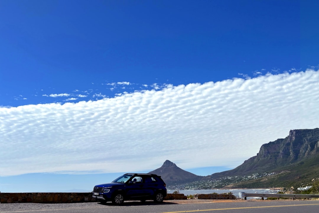The left front side of the Hyundai Venue parked with the mountains and sea in the background under a blue sky.