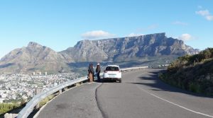 A white van driving down a curvy road next to a mountain