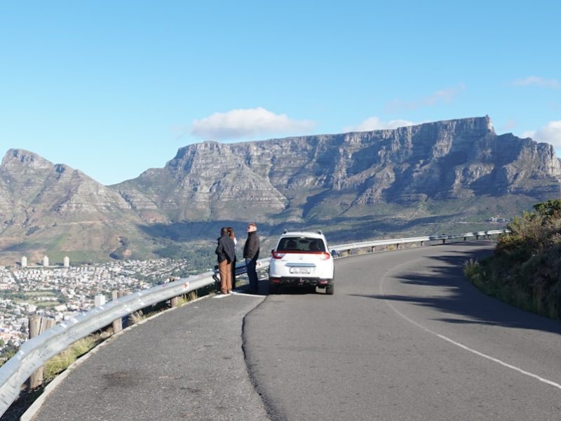A white van driving down a curvy road next to a mountain