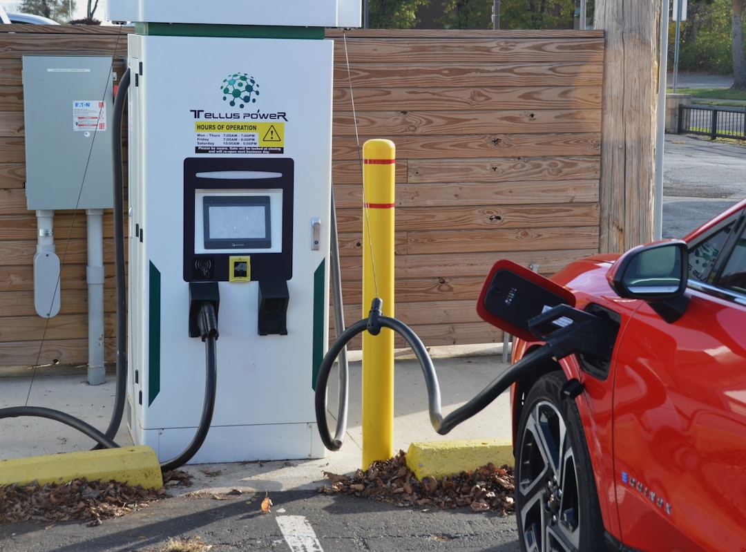 Red electric vehicle connected to a Tellus Power DC fast charging station with digital display and payment interface