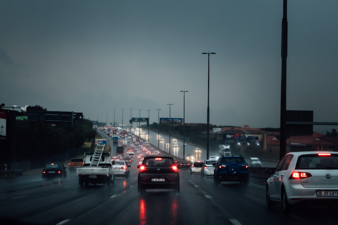 Multi-lane highway in rainy weather with traffic during dusk, headlights and taillights illuminated