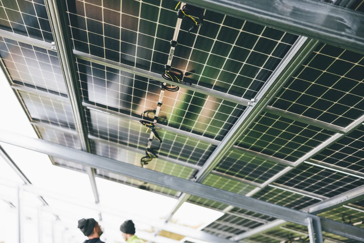 Solar panels mounted on ceiling with electrical distribution cables and connectors suspended below for power management