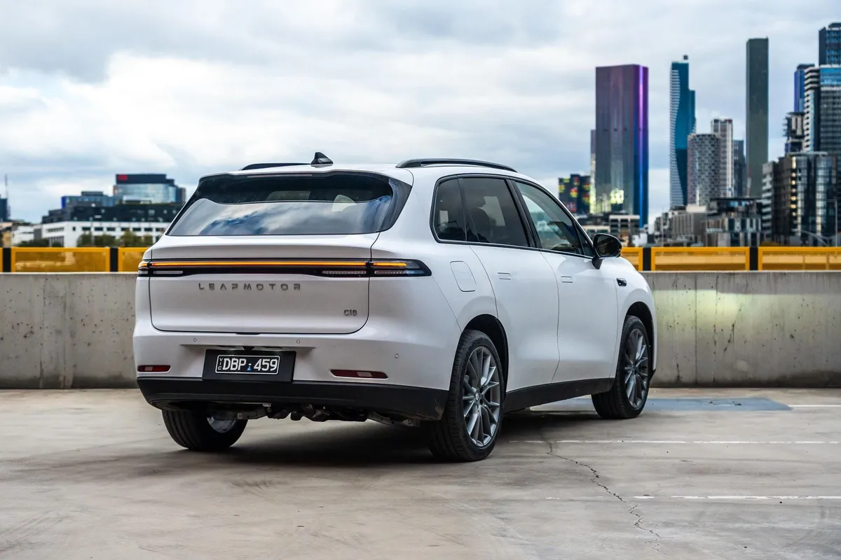 White Leapmotor C10 REEV parked in multi-story car park with city skyline backdrop