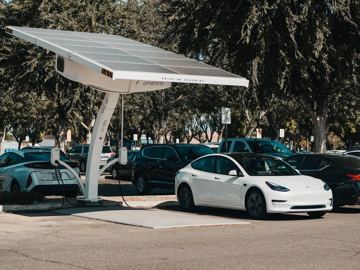 Solar canopy with integrated EV chargers at public parking lot with white Tesla and other vehicles