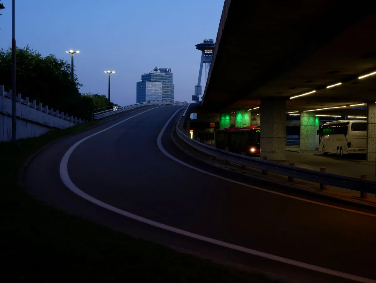 Electric buses parked under modern depot canopy with charging infrastructure and LED lighting at dusk