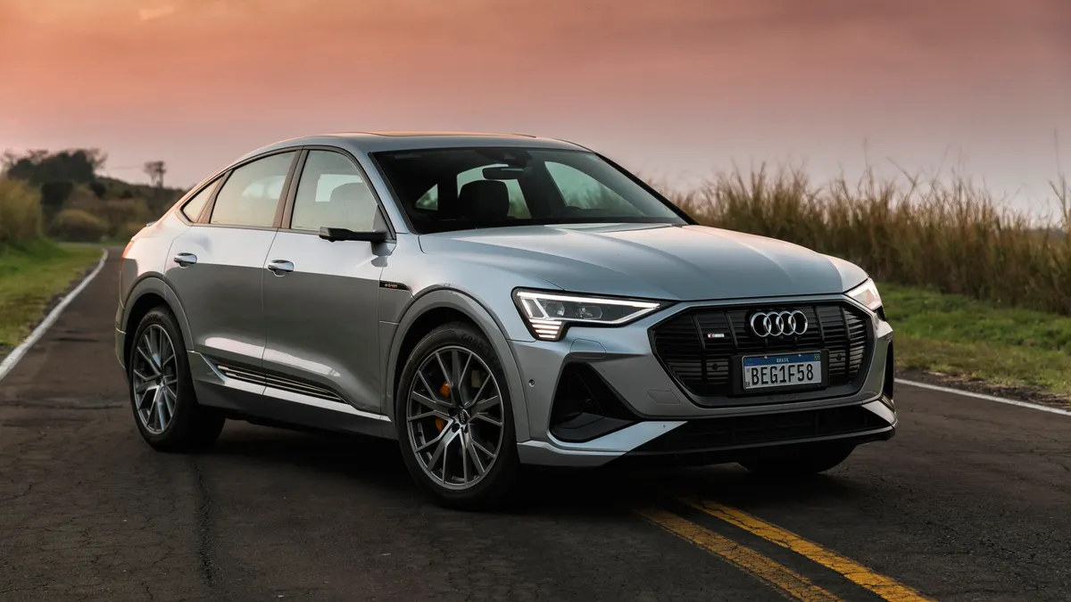 Silver Audi e-tron 55 quattro electric SUV parked on a road with grassland in background
