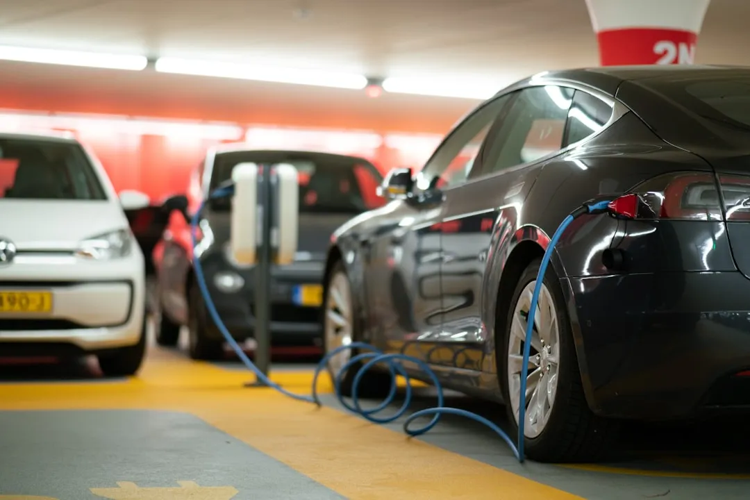 Multiple electric vehicles charging simultaneously at an indoor fleet depot with blue charging cables