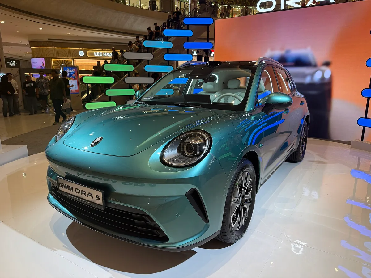 GWM Ora 5 BEV in turquoise-green, displayed in a modern showroom with teal lighting accents