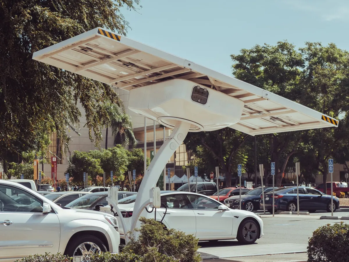 Solar panel canopy with integrated EV charger in public parking lot, vehicle charging underneath
