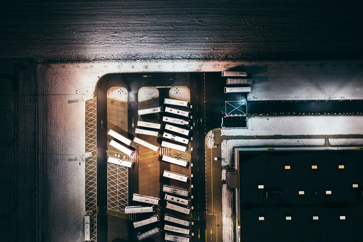 Overhead view of commercial EV charging depot with multiple buses parked at charging bays in organized rows