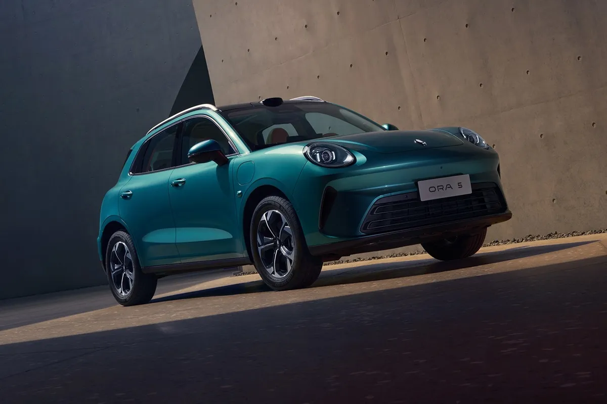GWM Ora 5 electric car in teal displayed against a concrete wall in a showroom setting