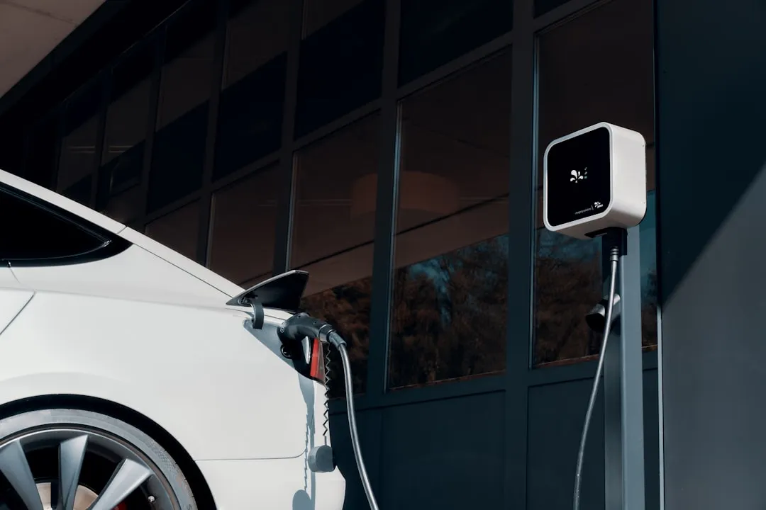 White electric vehicle charging via cable connected to white wall-mounted public charger on building exterior