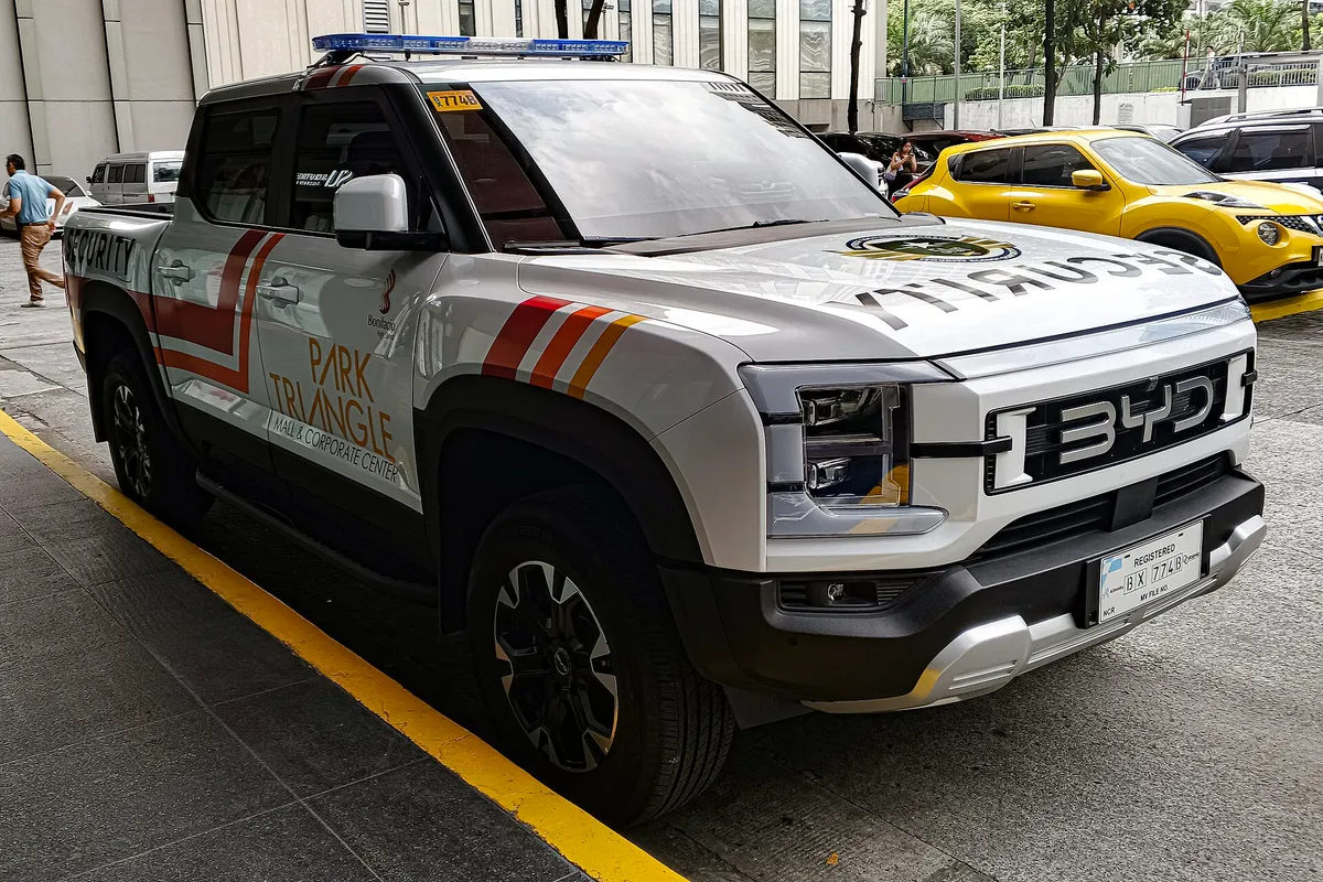 BYD Shark 6 pickup truck with white and black custom wrap parked on street