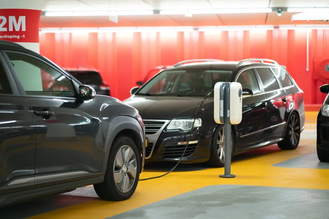 Electric vehicles charging at modern station in covered parking facility with red barriers