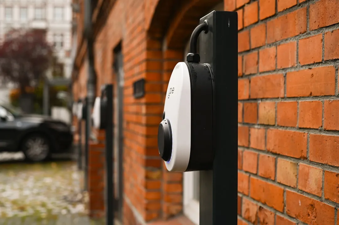 White and black wall-mounted EV charging unit installed on orange brick exterior of residential home