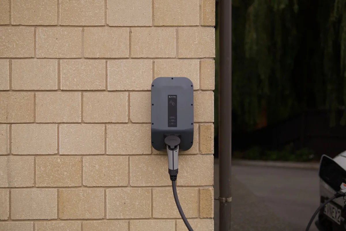 Wall-mounted EV charger installation on brick residential property with mounted charging cable