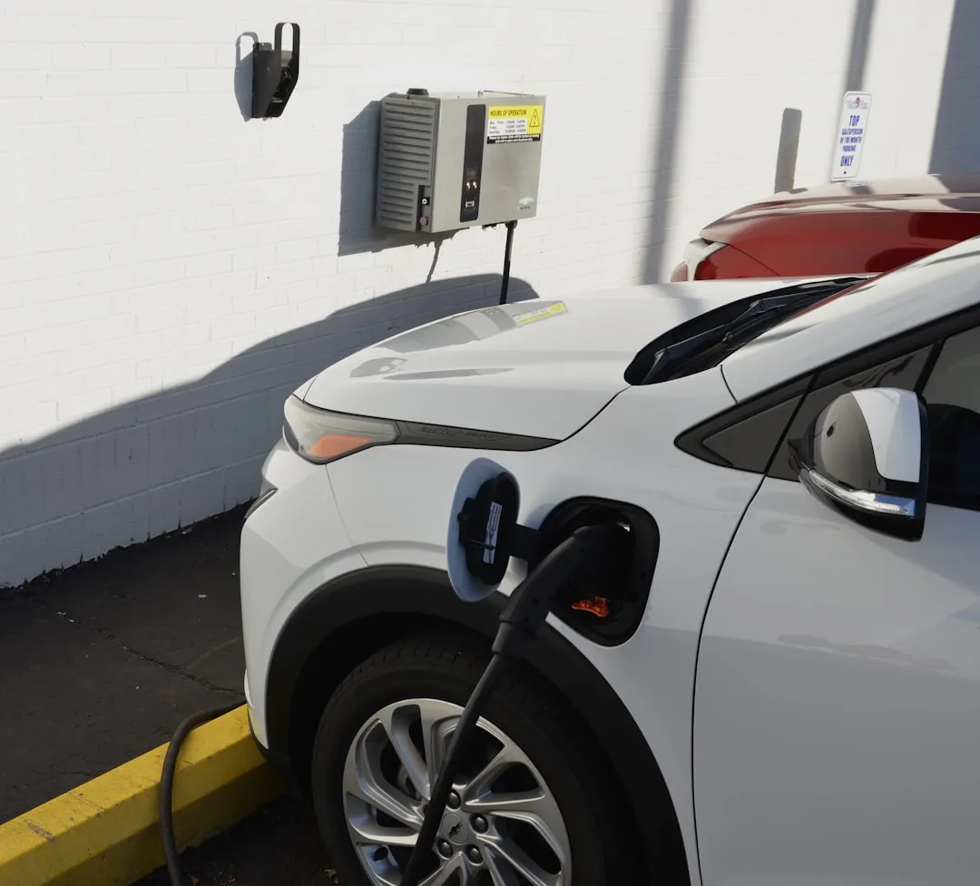 Wall-mounted EV charger with cable connected to white electric vehicle in designated parking space