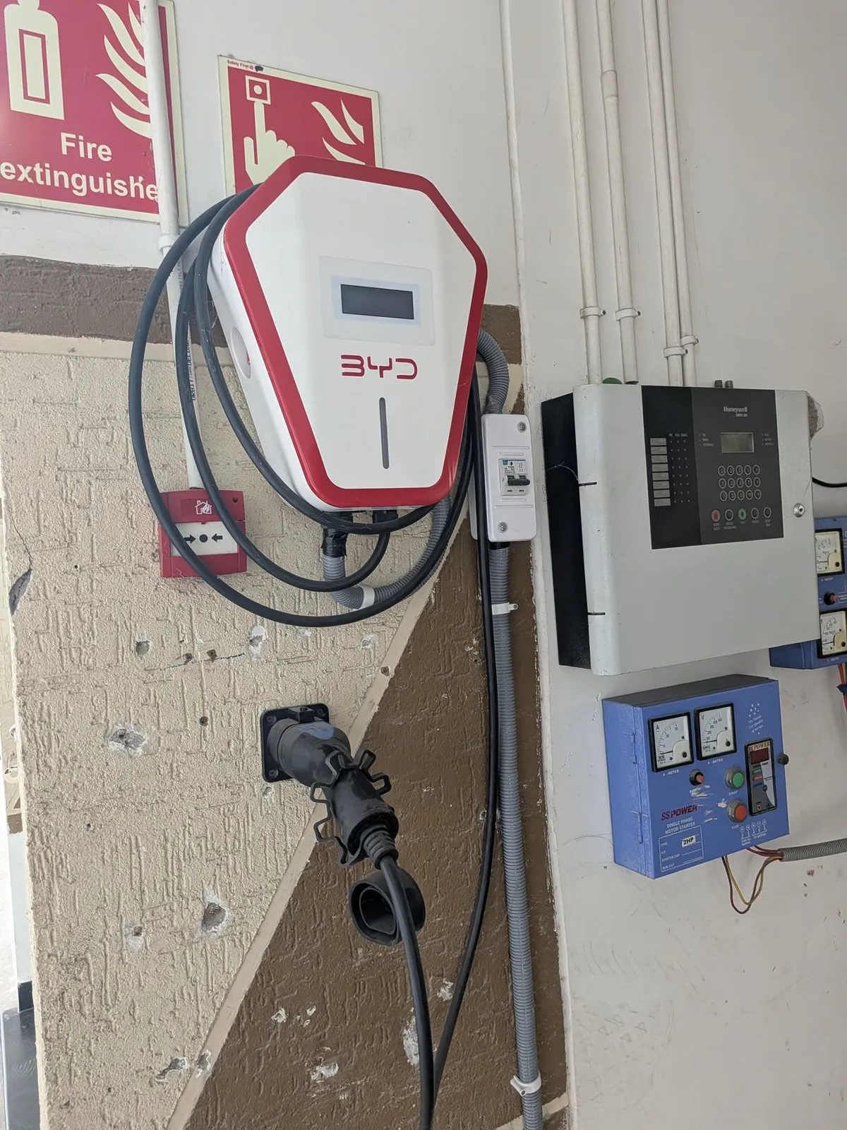 A BYD-branded home wallbox wall-mounted beside an electrical distribution board