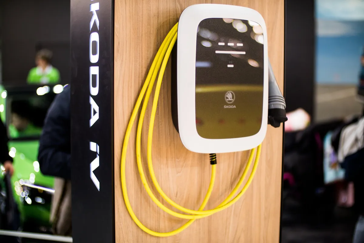 A Skoda iV home wallbox with a tethered yellow Type-2 cable